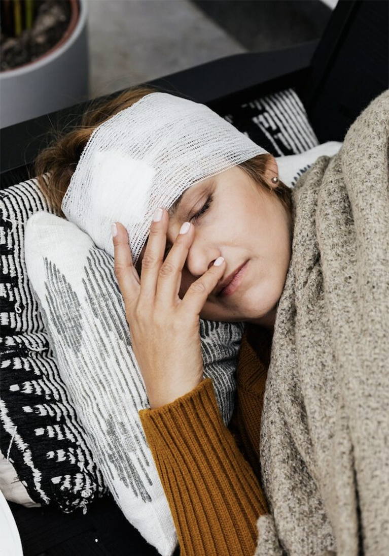 Woman with a TBI lying down with a bandage on her head.