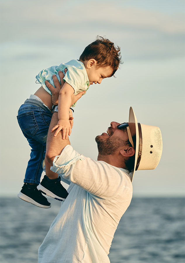 Happy dad holding up son at the beach